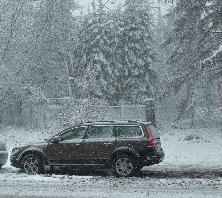 An SUV in snowy conditions with trees in the background